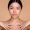 Beauty, care skin concept. Beautiful chinese brunette young woman, with perfect skin and naked shoulders, posing with hands near collarbone at isolated beige background, look at camera, smile pleasant